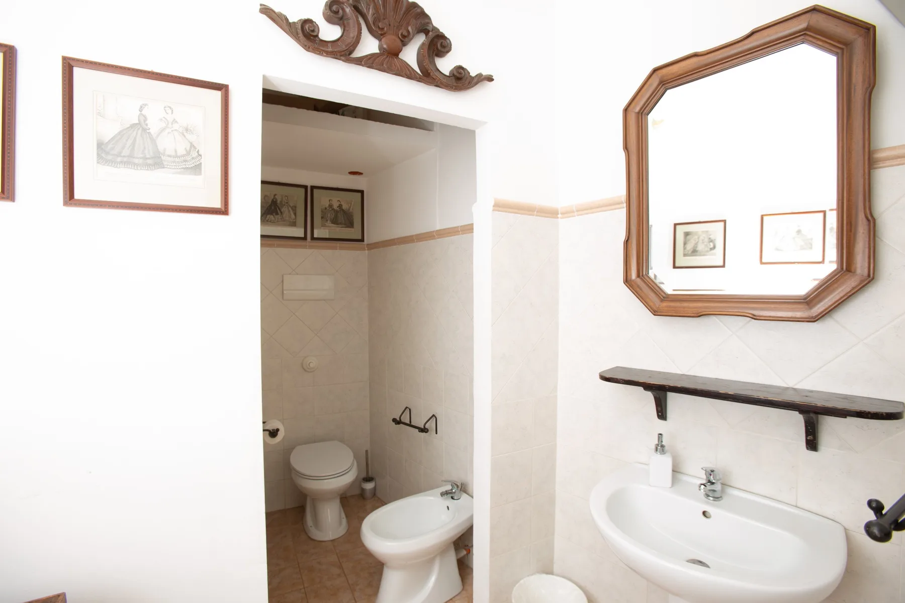 Un baño con inodoro, bidé y lavabo bajo un espejo de pared.