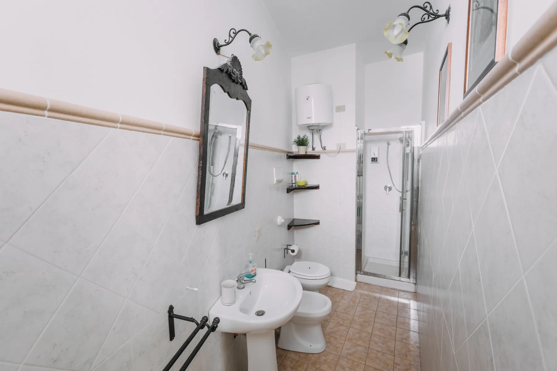 Un baño alicatado con un lavabo de pared y una ducha.