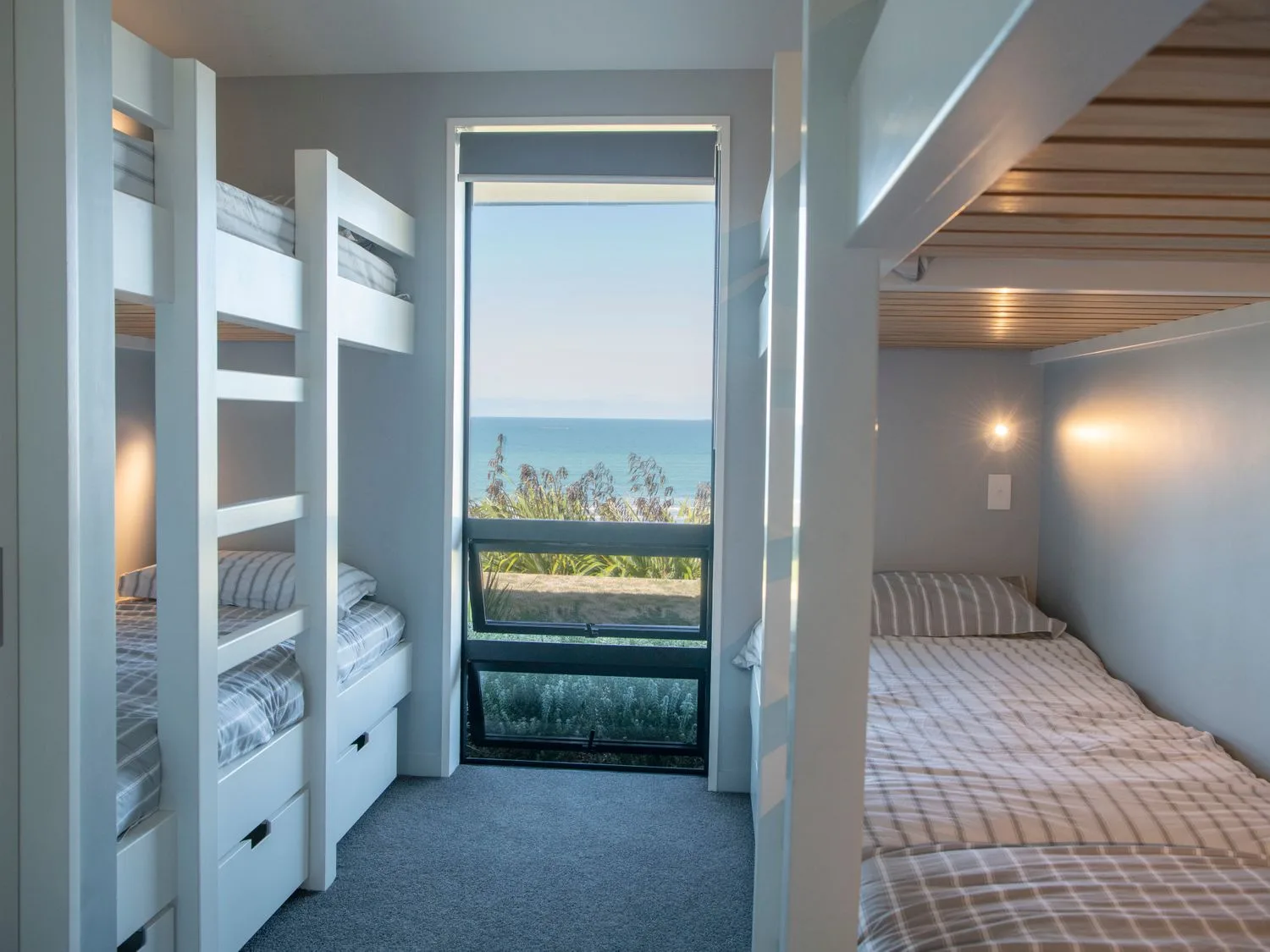 A bedroom with bunk beds beside a window overlooking the sea.