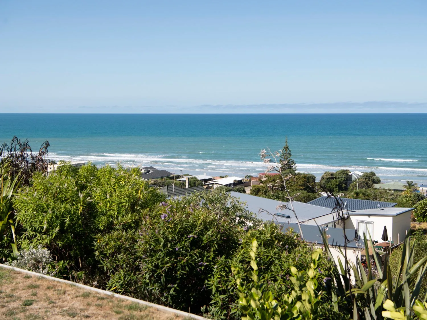 A coastal view with houses and vegetation overlooking the ocean at Lightning Ridge Views Waimarama
