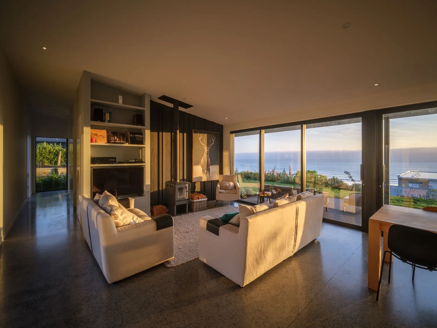 A living room with sofas a wood stove and large sliding glass doors overlooking the ocean at Lightning Ridge Views - Waimarama Holiday Home in Waimarama