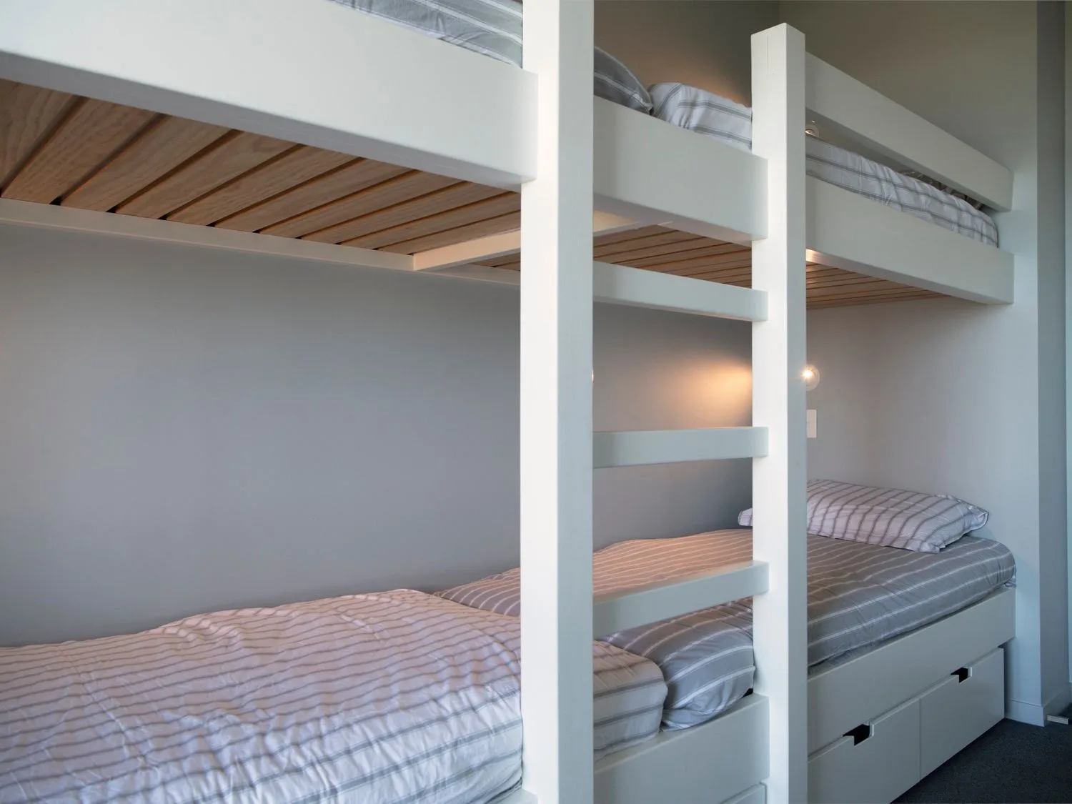 A bedroom with white bunk beds and striped bedding at Lightning Ridge Views - Waimarama Holiday Home in Waimarama