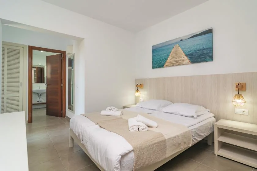 A bedroom with a double bed beneath a coastal walkway picture.