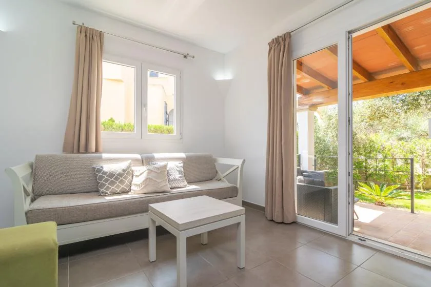 A bright living room has a sofa, coffee table, and sliding glass doors opening to a patio.