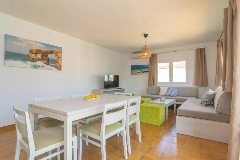 A bright living and dining room with a white table and seating beside a sofa.