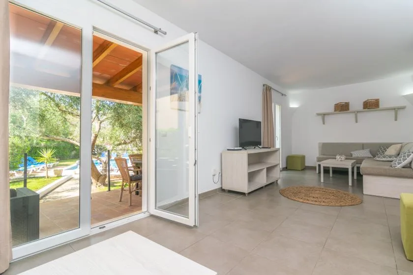 A bright living room opens onto a patio through wide glass doors.