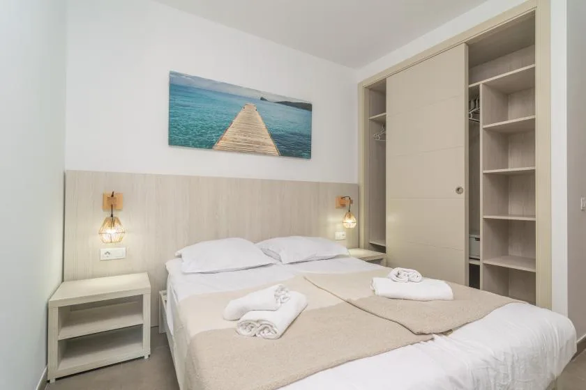 A bedroom with a double bed, bedside tables, and an open wardrobe.