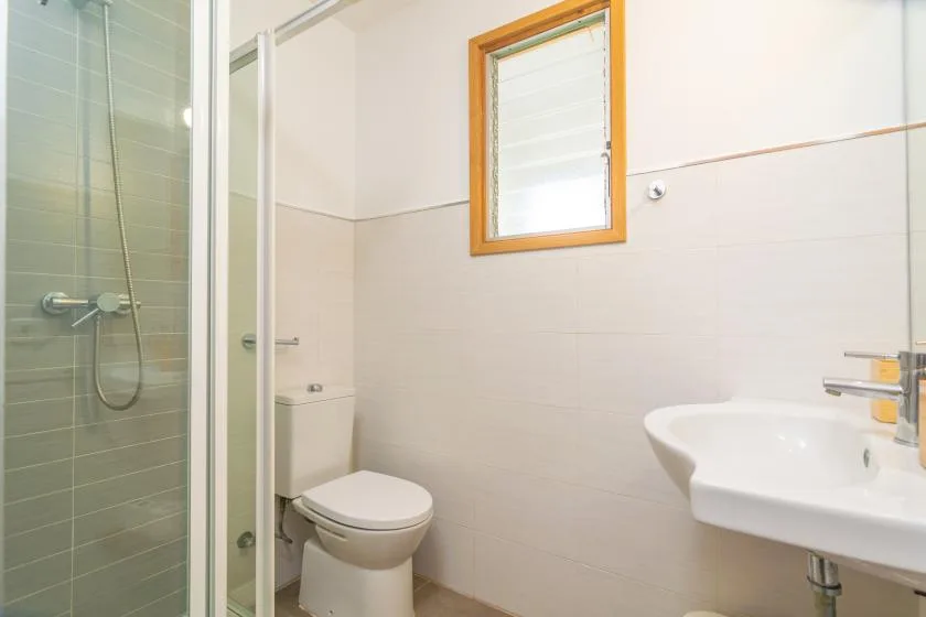 A bathroom with a glass shower, toilet, and sink.