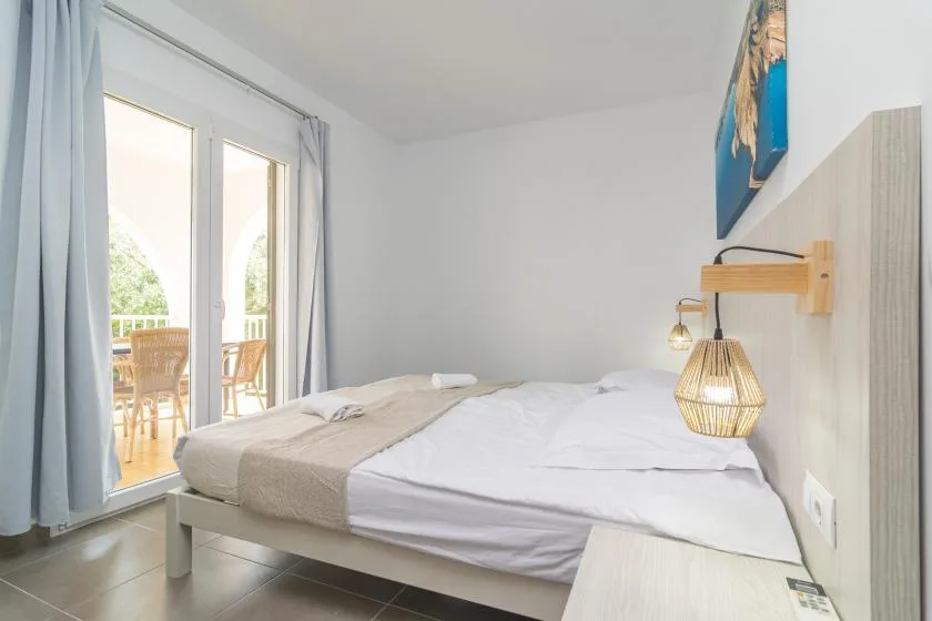 A bedroom with a bed beside a glass door opening onto a balcony.