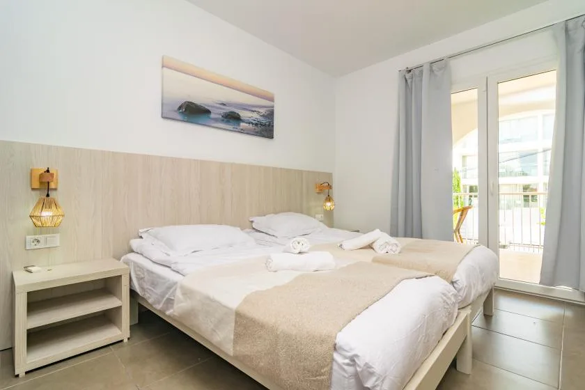 A bedroom with a neatly made bed and sliding glass doors opening onto a balcony.