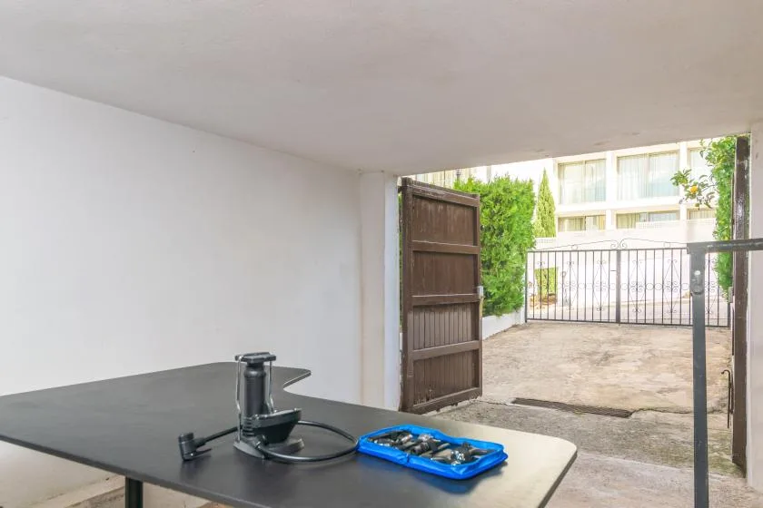 A covered patio area opens onto a paved courtyard through a wooden gate.