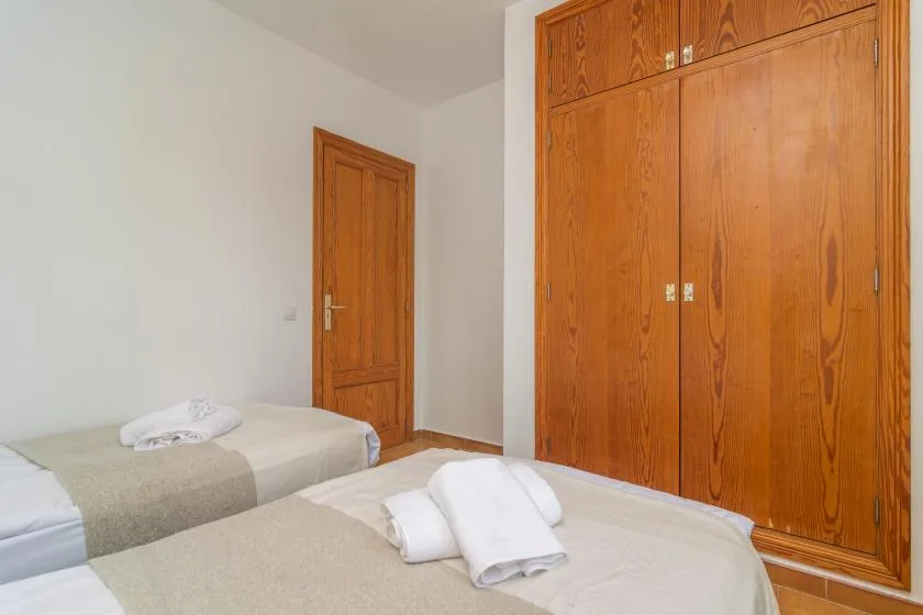 A bedroom with two beds and wooden wardrobes.