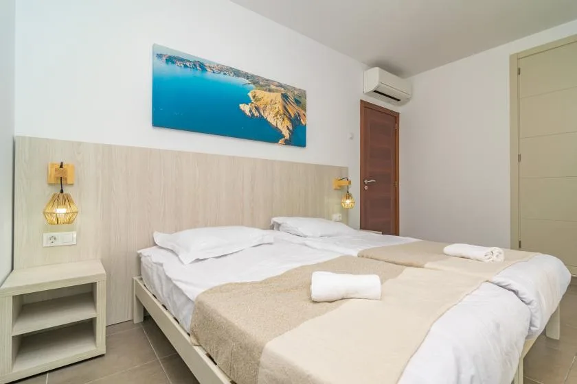 A bedroom with a neatly made bed and a coastal landscape print above it.