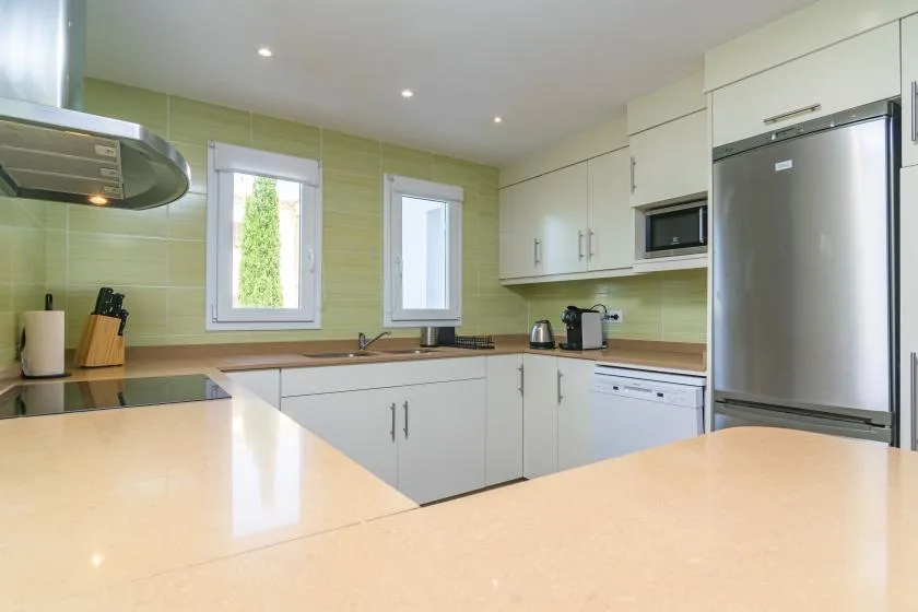 A bright kitchen with pale cabinets, a countertop, and stainless steel appliances.