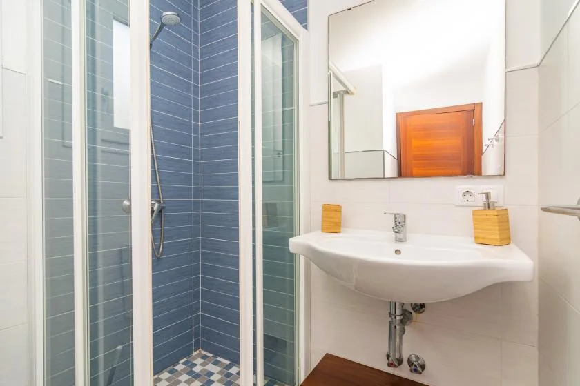 A bathroom with a sink and a glass-enclosed shower.