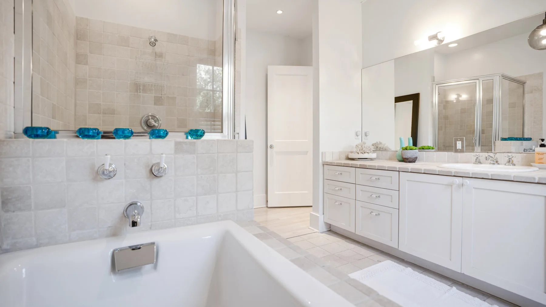 Un baño luminoso con bañera, tocador y zona de ducha con espejo.
