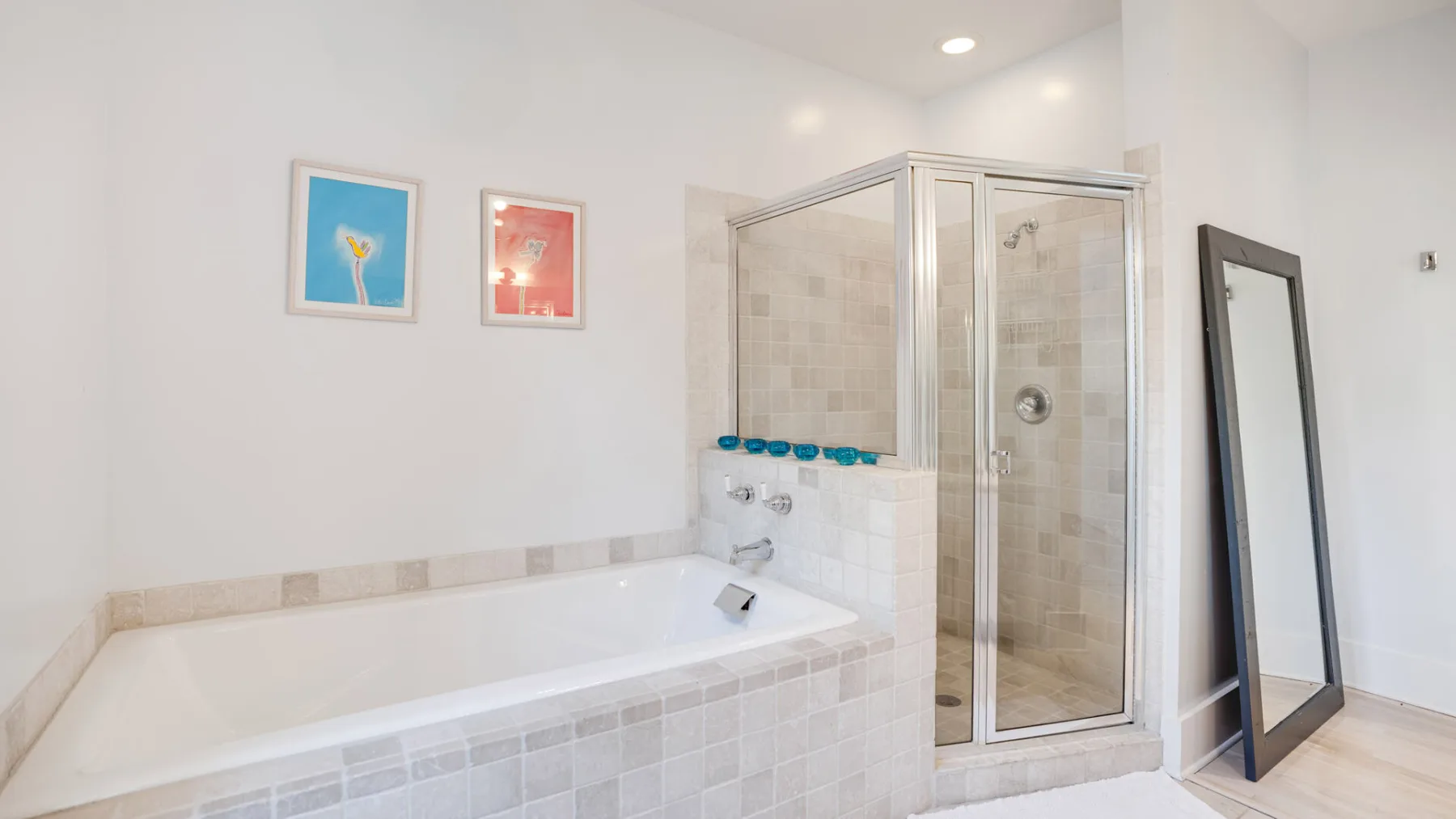 Un baño con bañera y una ducha con mampara de vidrio.