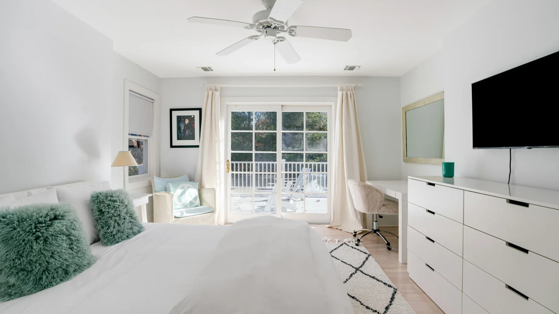 Un dormitorio luminoso con una cama, una ventana grande y un televisor.