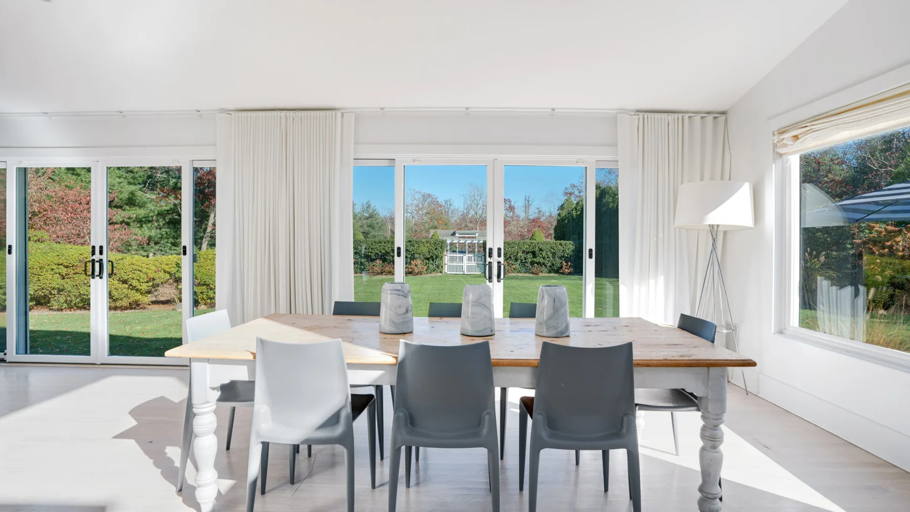 Un comedor luminoso con una mesa larga y sillas junto a grandes ventanales.