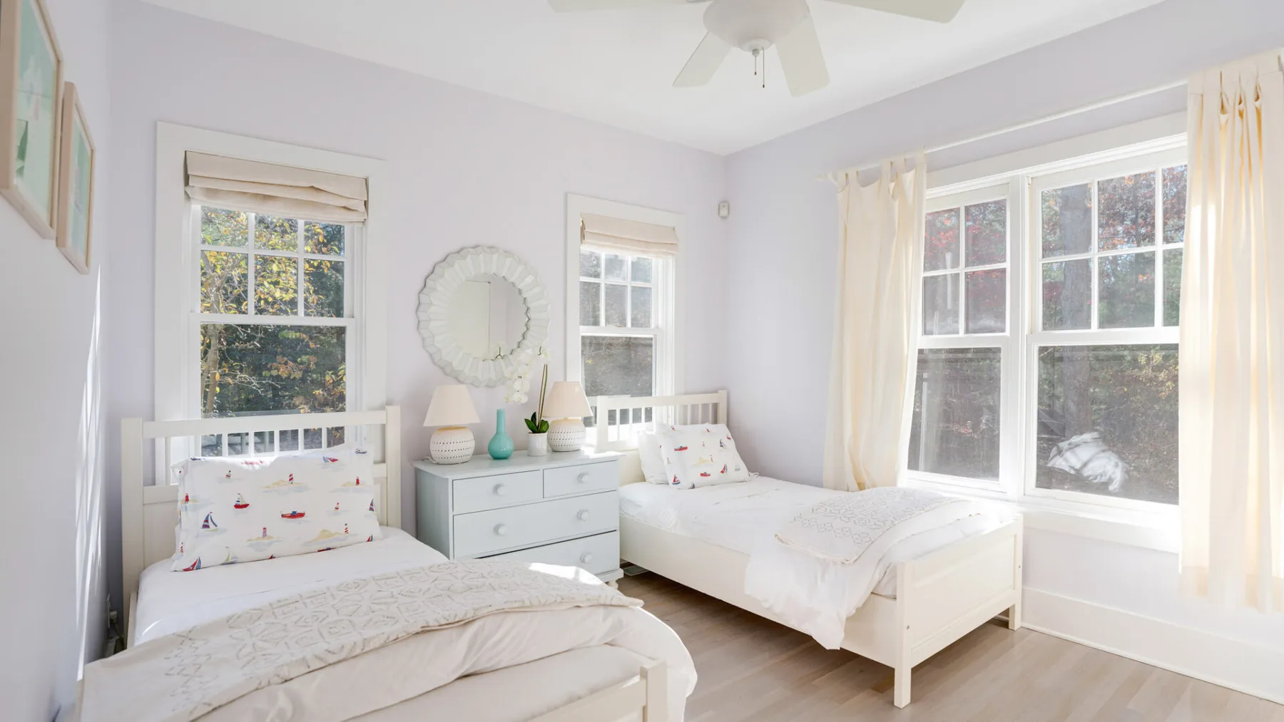 Un dormitorio luminoso con dos camas y ventanas grandes.