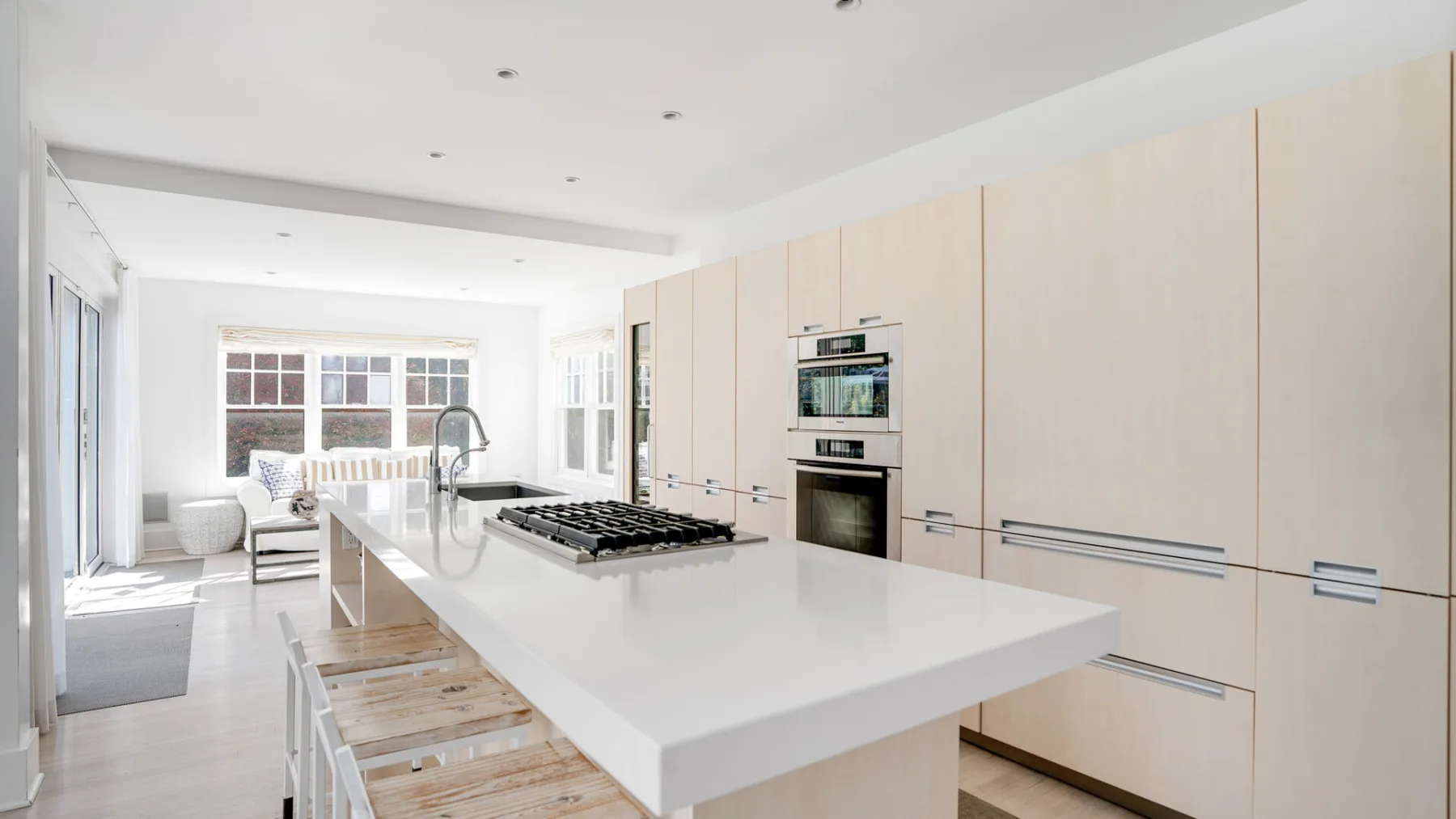 Una cocina luminosa con una gran isla, una placa de cocina y un horno empotrado.