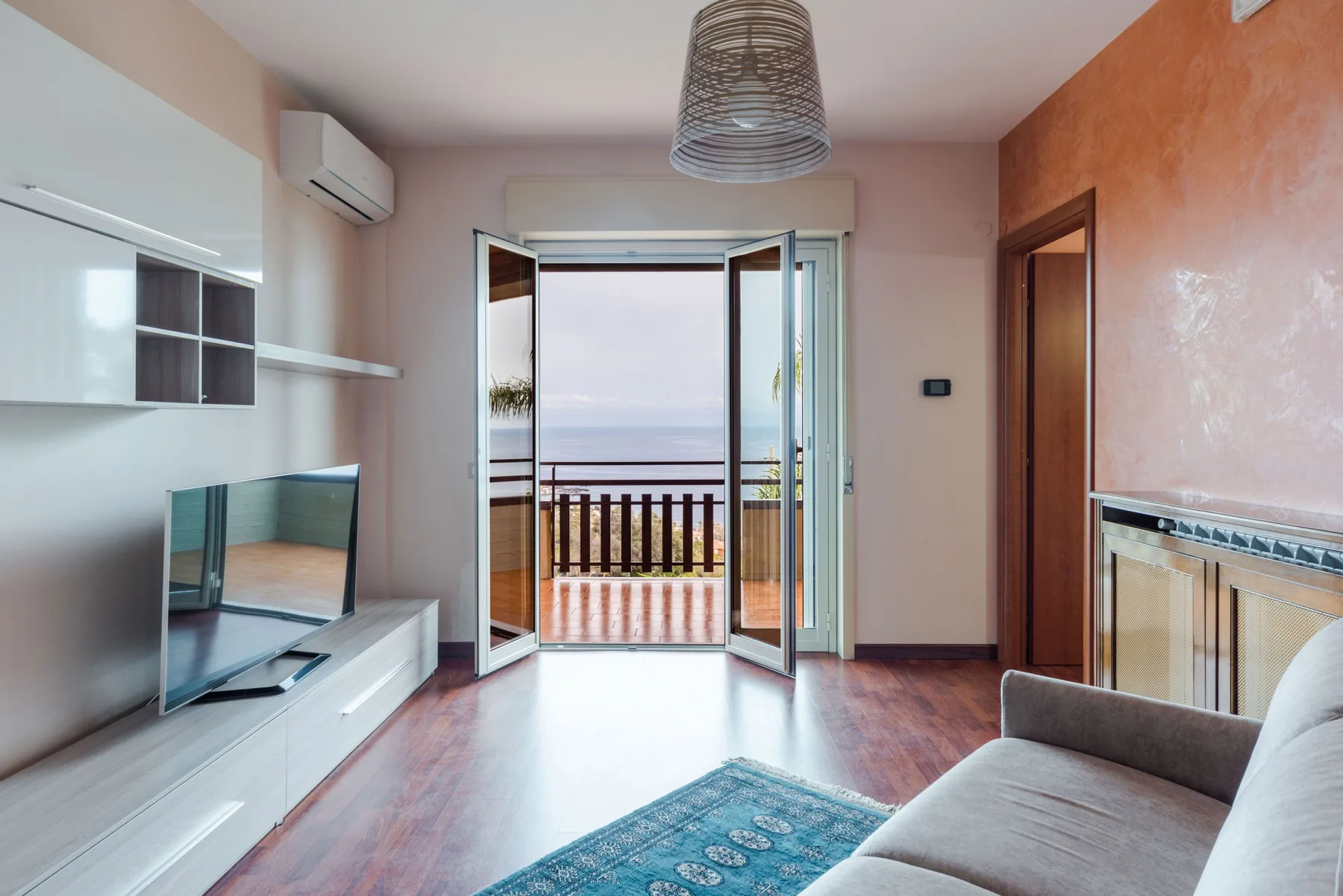 A living room opens onto a balcony through wide glass doors.