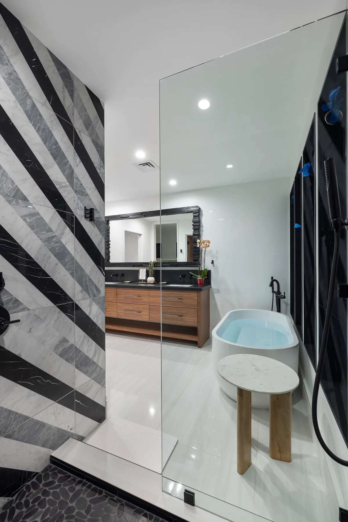 Un baño moderno con bañera exenta, tocador y mampara de ducha de vidrio.