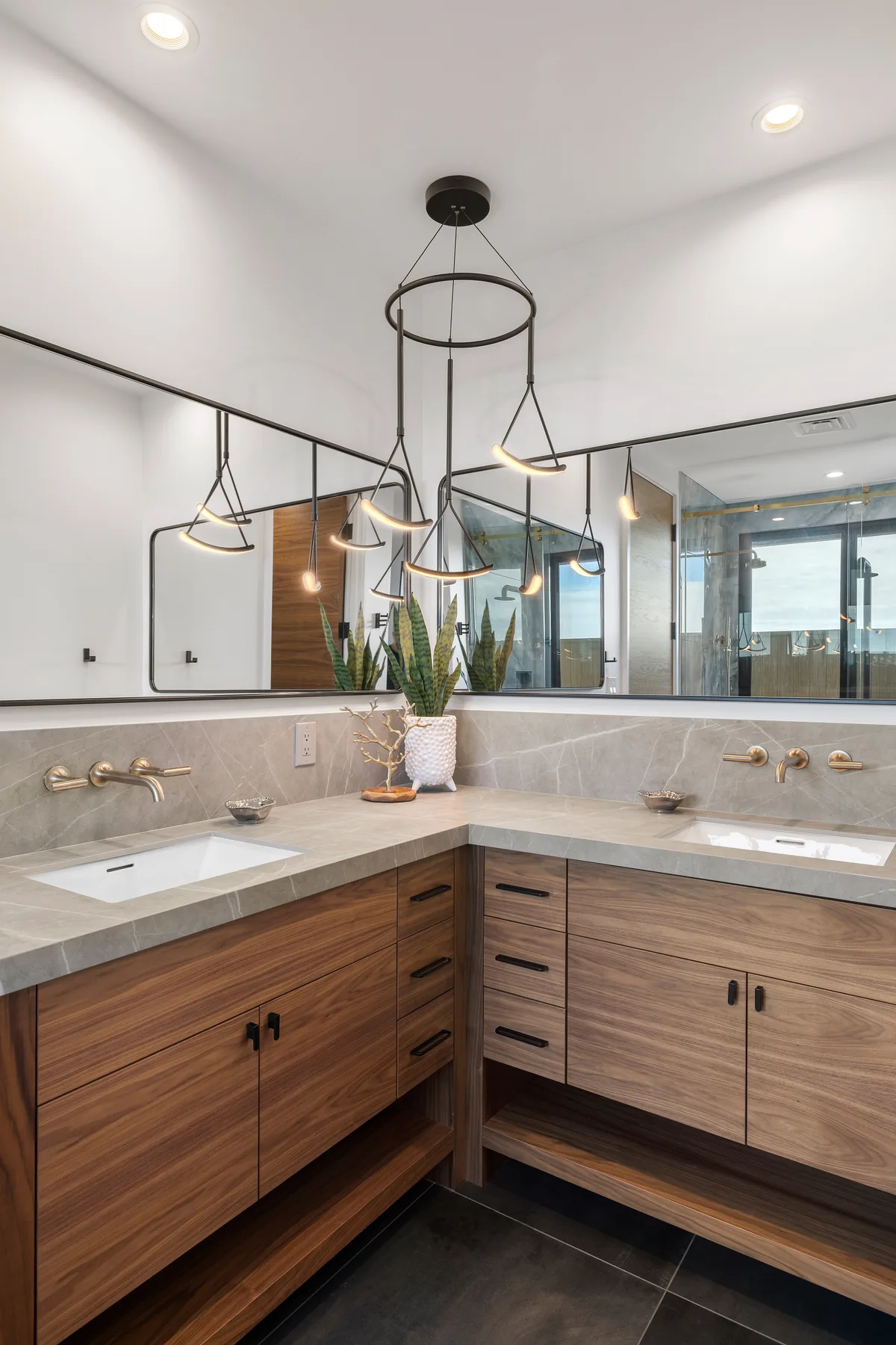 Un tocador de baño moderno con gabinetes de madera, encimeras claras y un espejo grande.