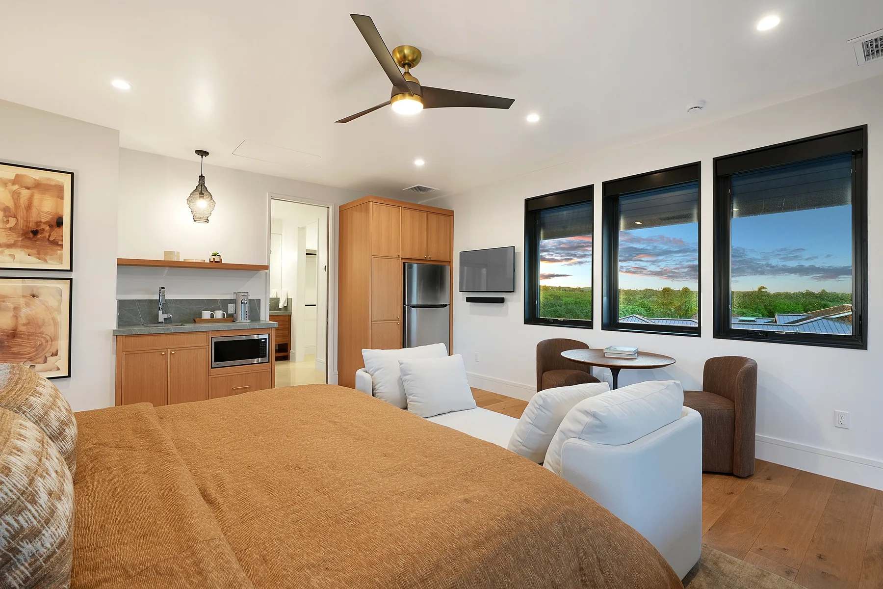 Dormitorio con cama, asientos y grandes ventanas con vistas al paisaje.