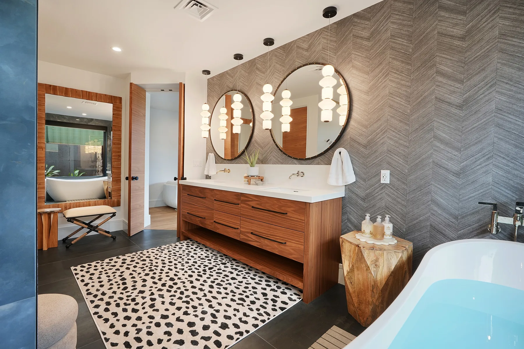 Un tocador de baño con espejos redondos, muebles de madera y una bañera.