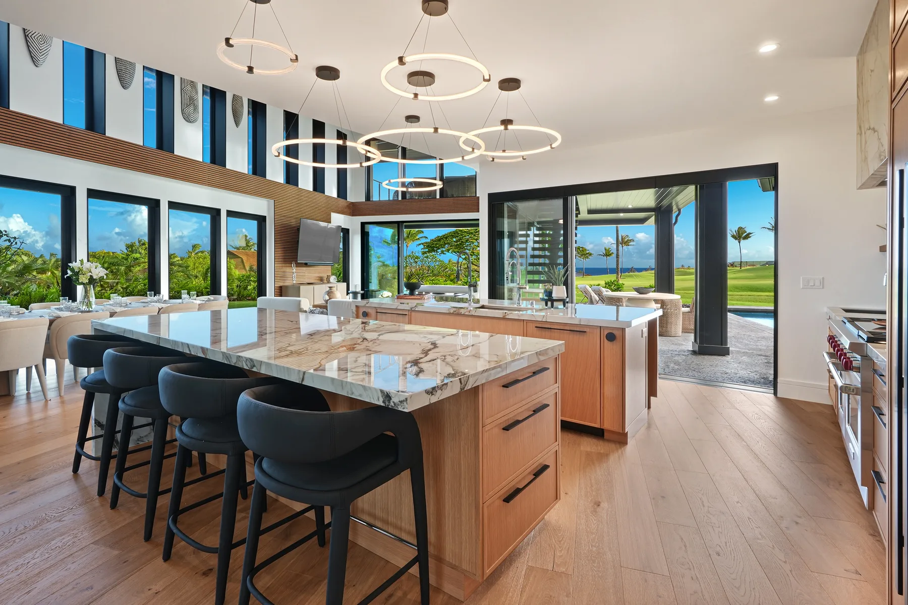 Una cocina amplia con una gran isla y asientos bajo lámparas colgantes.