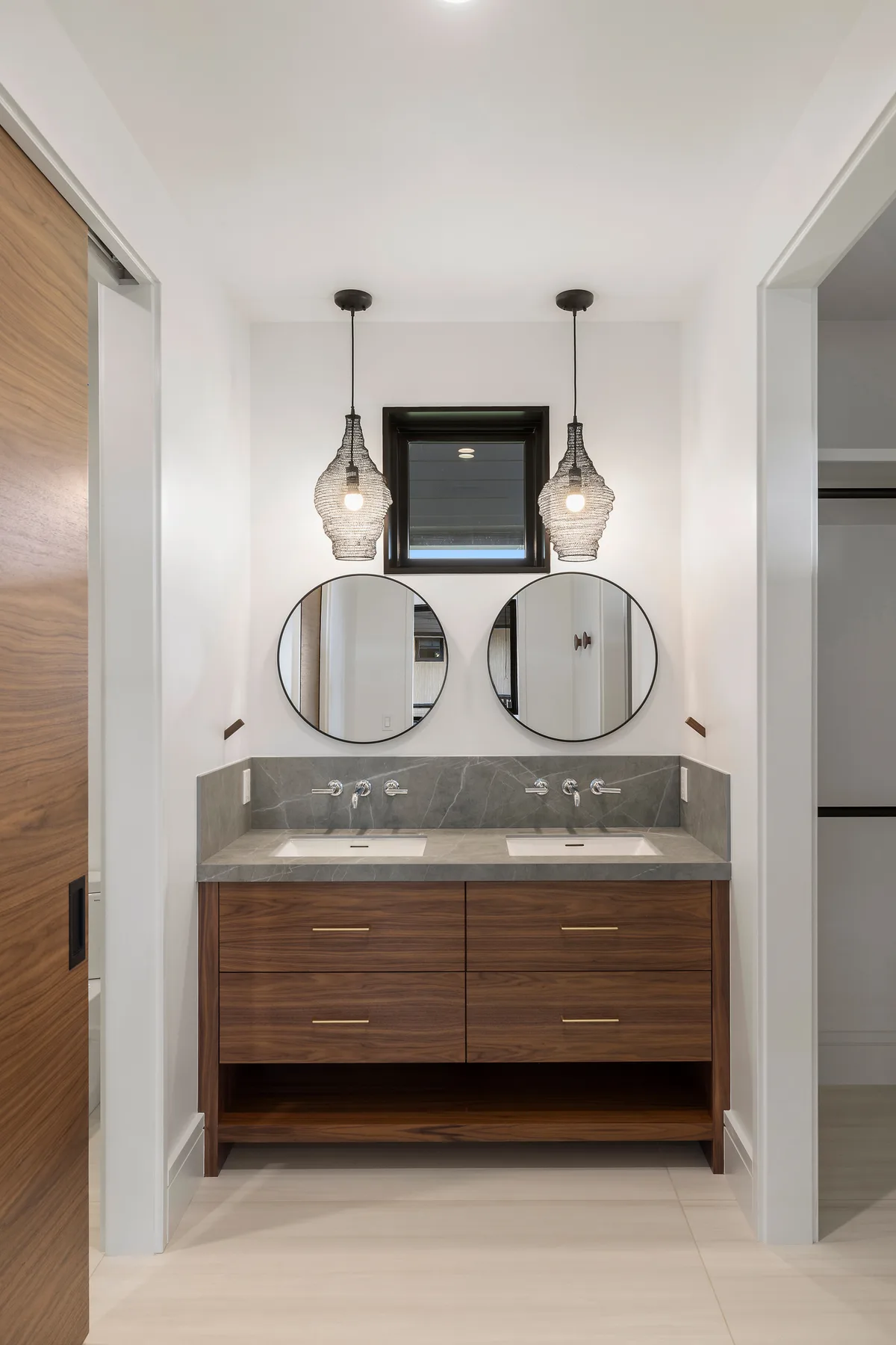 Un tocador de baño con dos espejos redondos y luces colgantes.