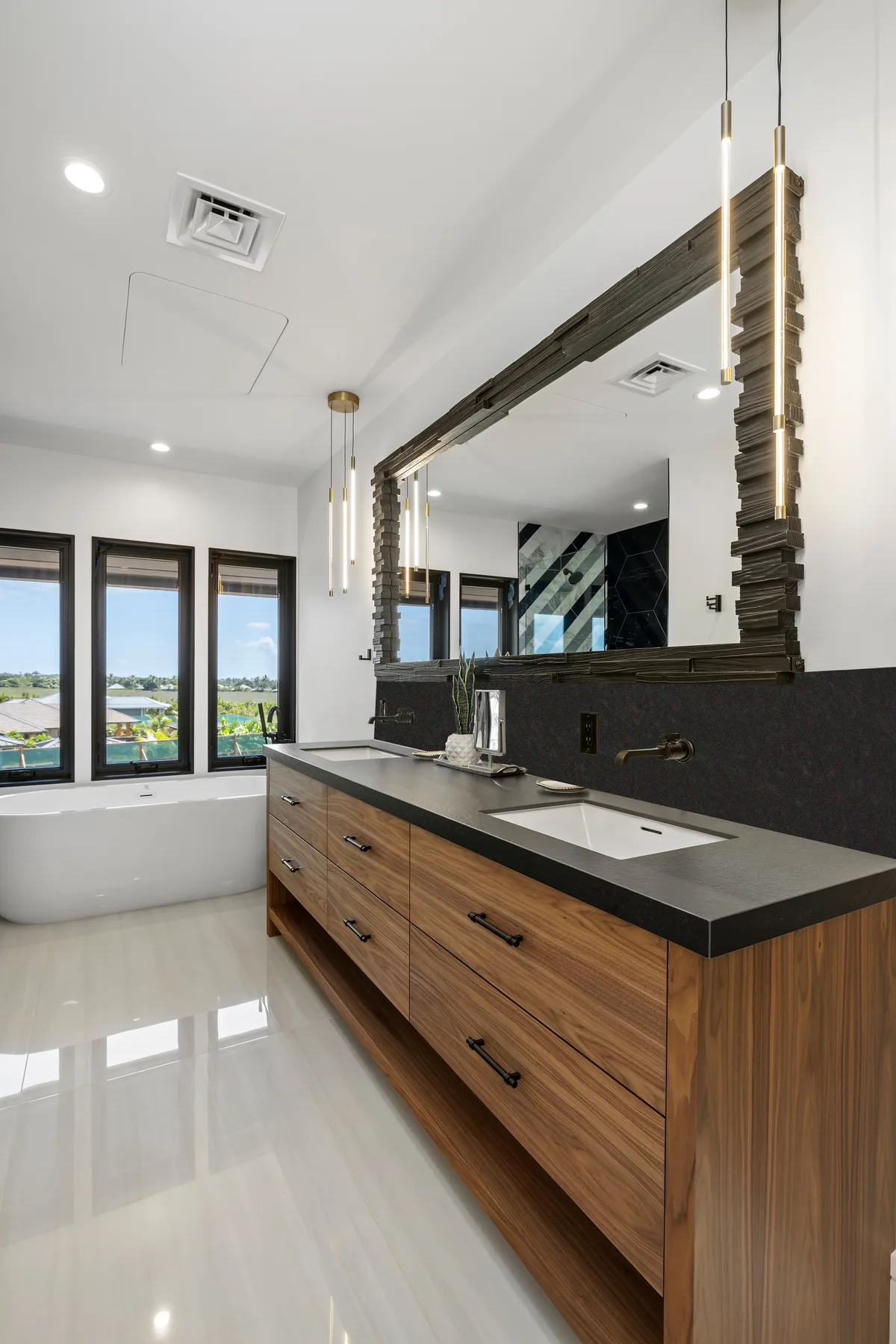 Un tocador de baño moderno con un espejo grande y ventanas con vistas al exterior.