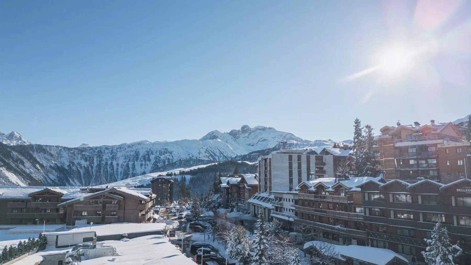 Snow-covered mountain buildings sit beneath a bright winter sky.
