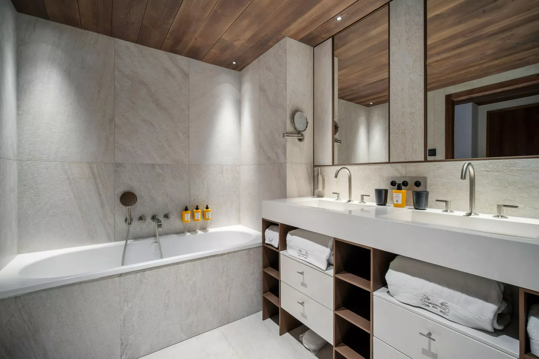 A modern bathroom with a bathtub, a wide vanity, and mirrors.