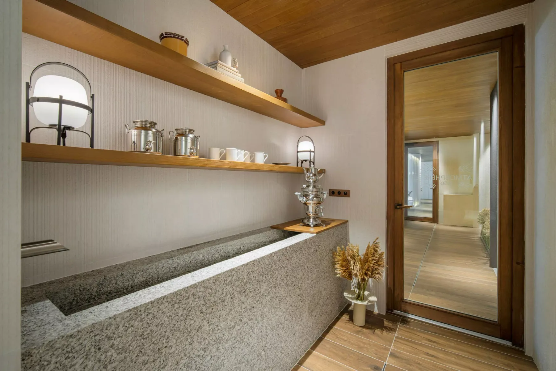 A hallway with a long built-in counter, open shelves, and a glass-paneled doorway.