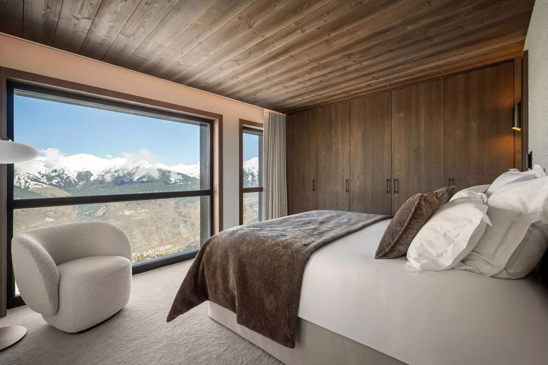 A bedroom with a large window overlooking a mountain landscape.