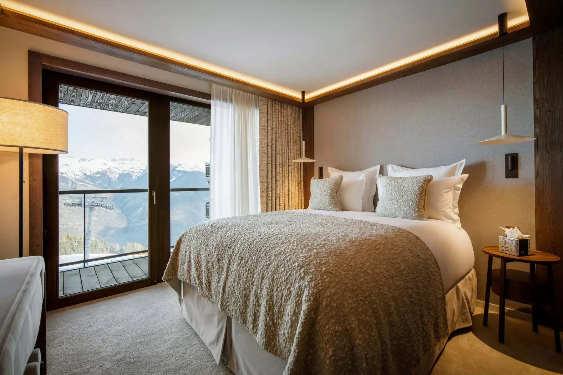 A bedroom with a large bed and glass doors opening onto a balcony.