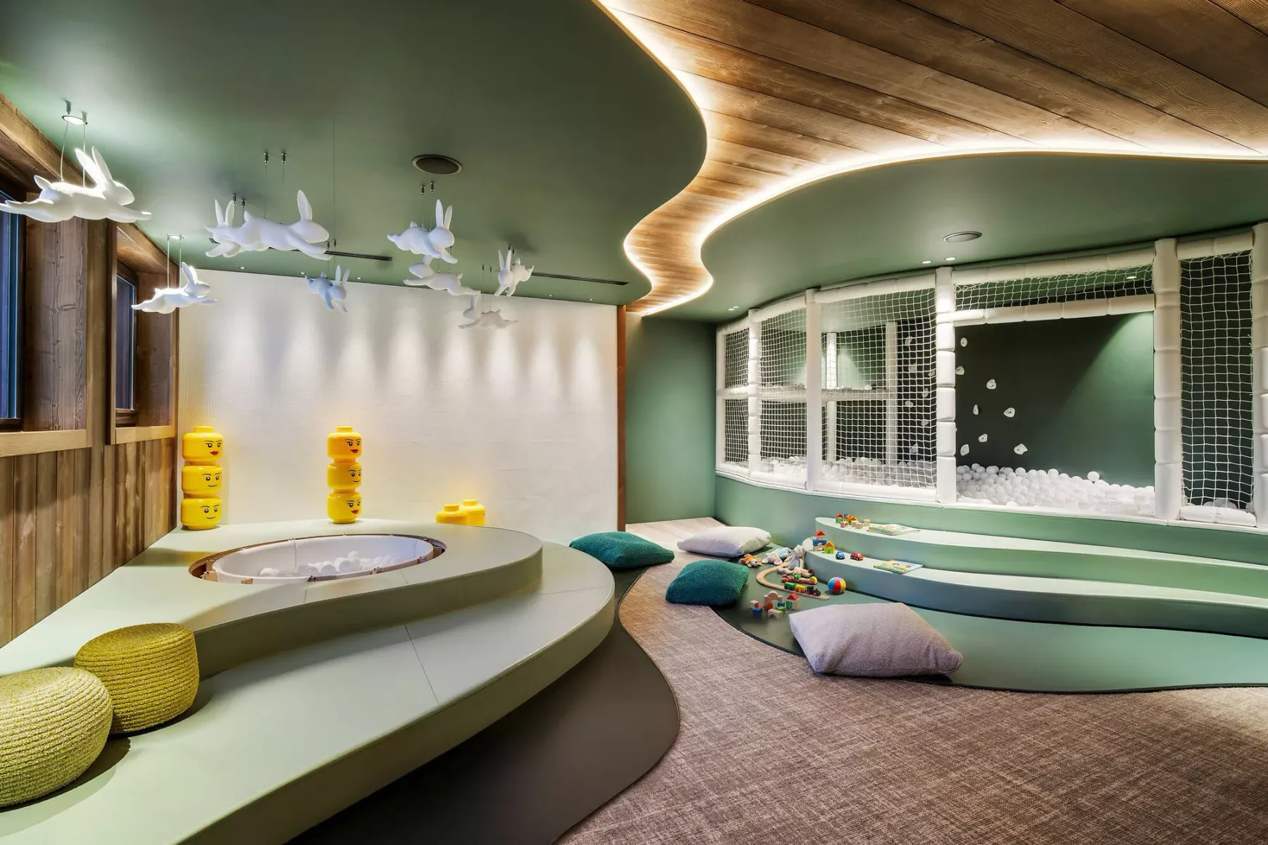 A colorful indoor playroom features curved seating and a low circular platform.