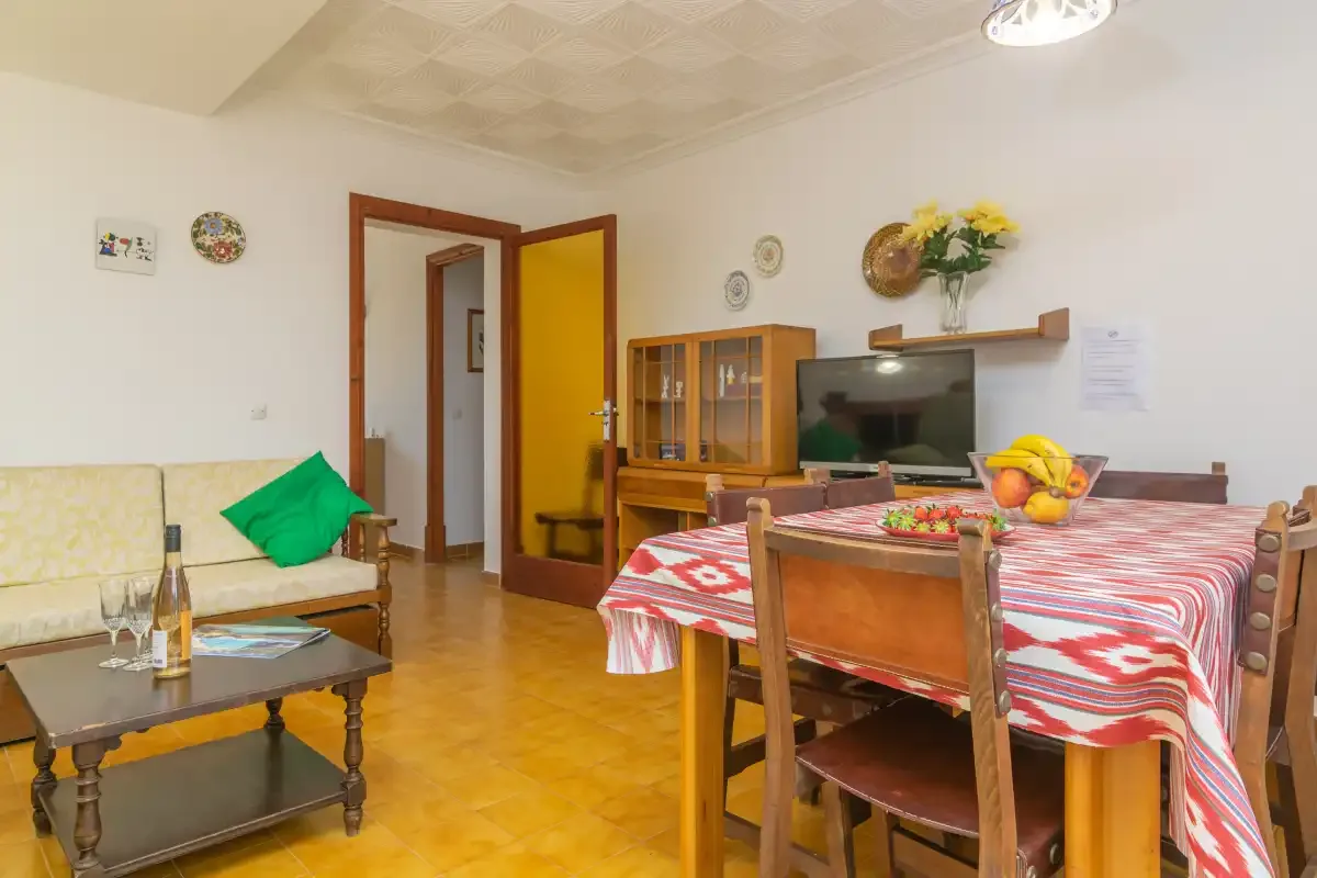 A dining and sitting room with a table covered in a red-and-white patterned cloth.