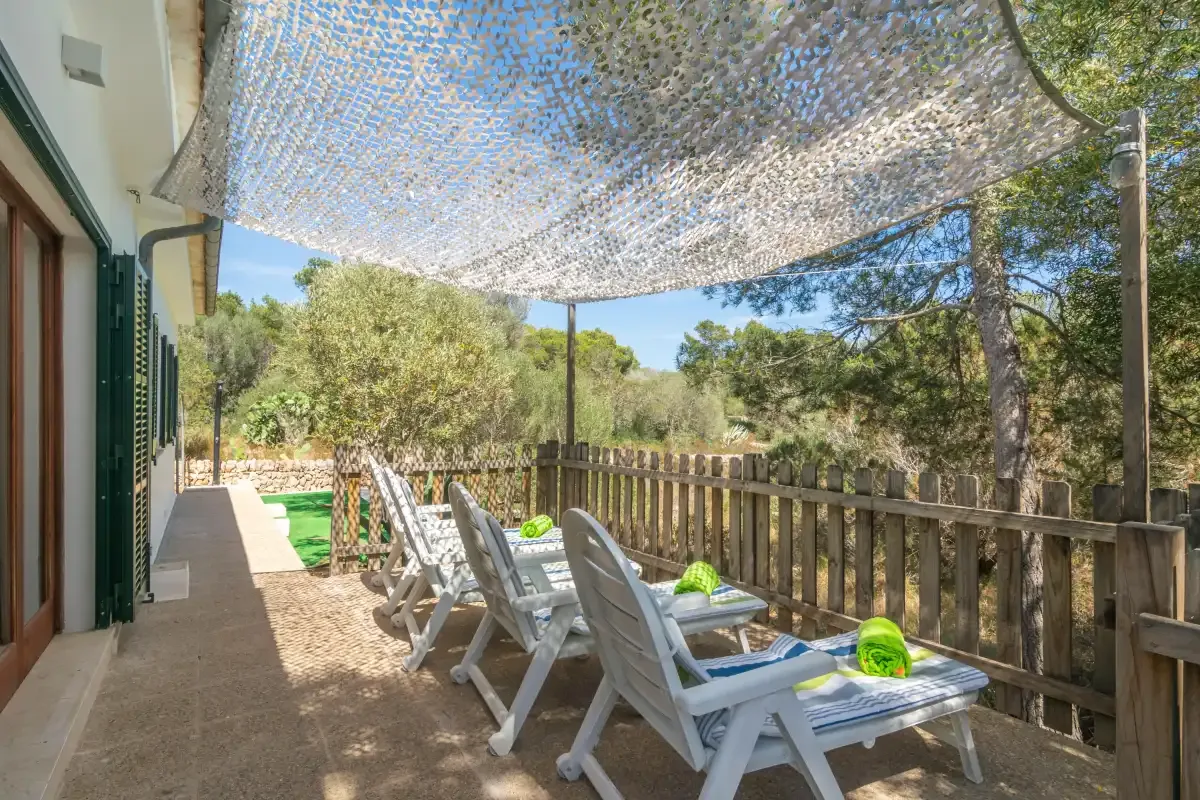 An outdoor patio with lounge seating beneath a shade canopy.