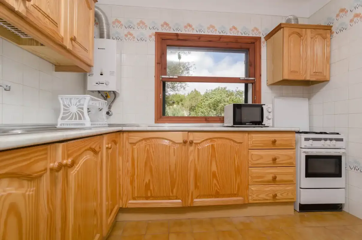 A kitchen with wooden cabinets, a countertop, and a window.