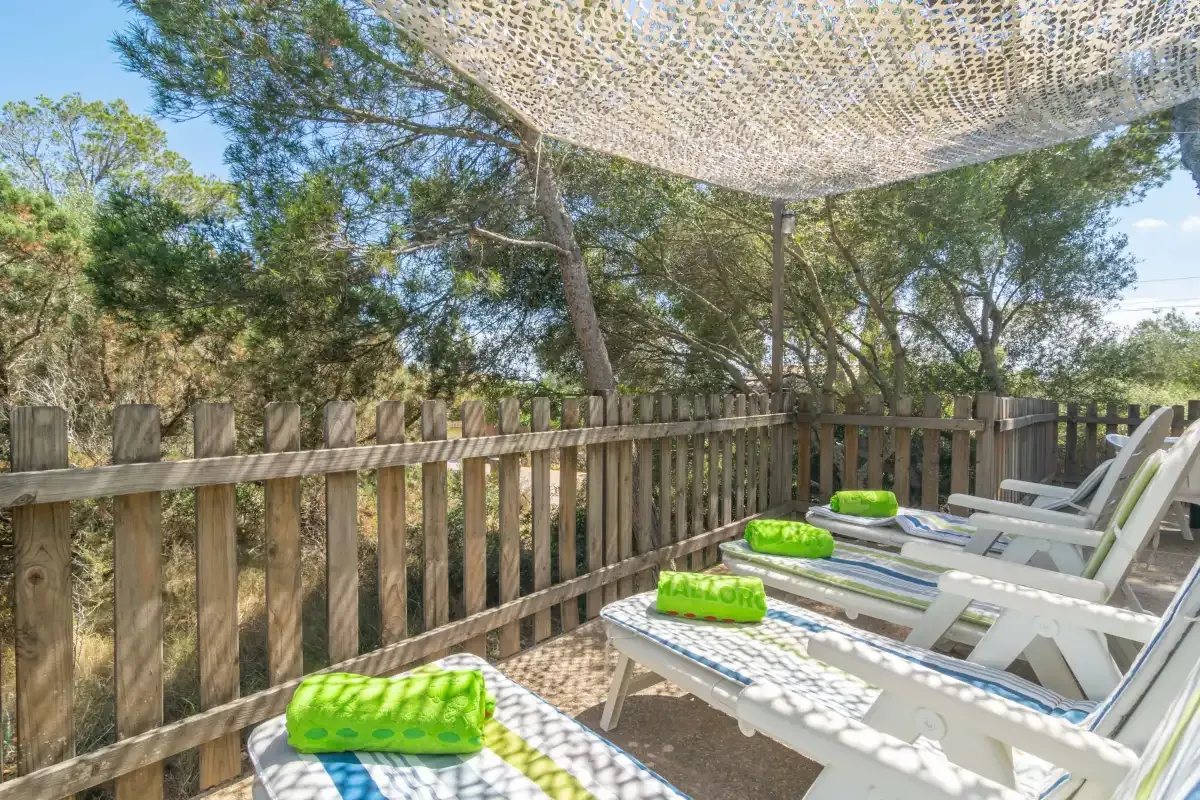 An outdoor deck has white lounge seating and green inflatable floats under a shade canopy.