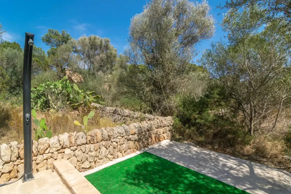 An outdoor swimming pool beside a stone wall and trees.