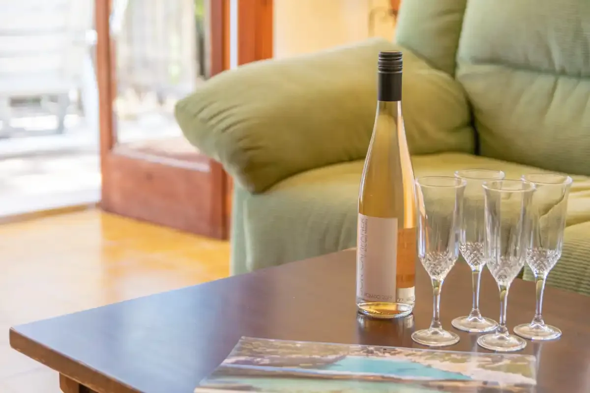A living room seating area with a coffee table, wine bottle, and glasses.