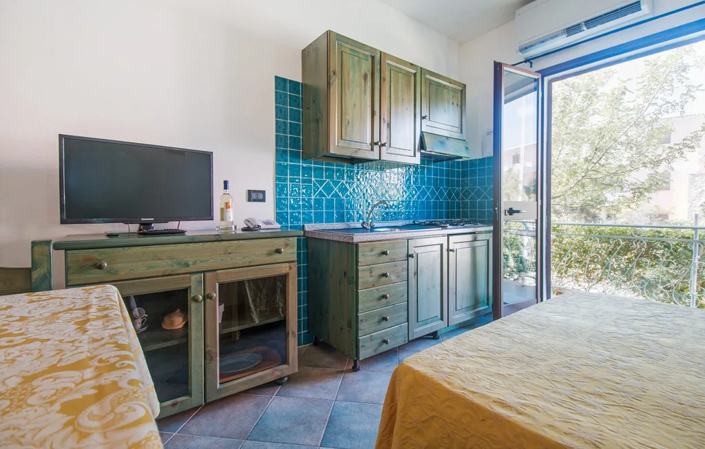 A compact kitchen with blue tile backsplash and an open glass door to a balcony.