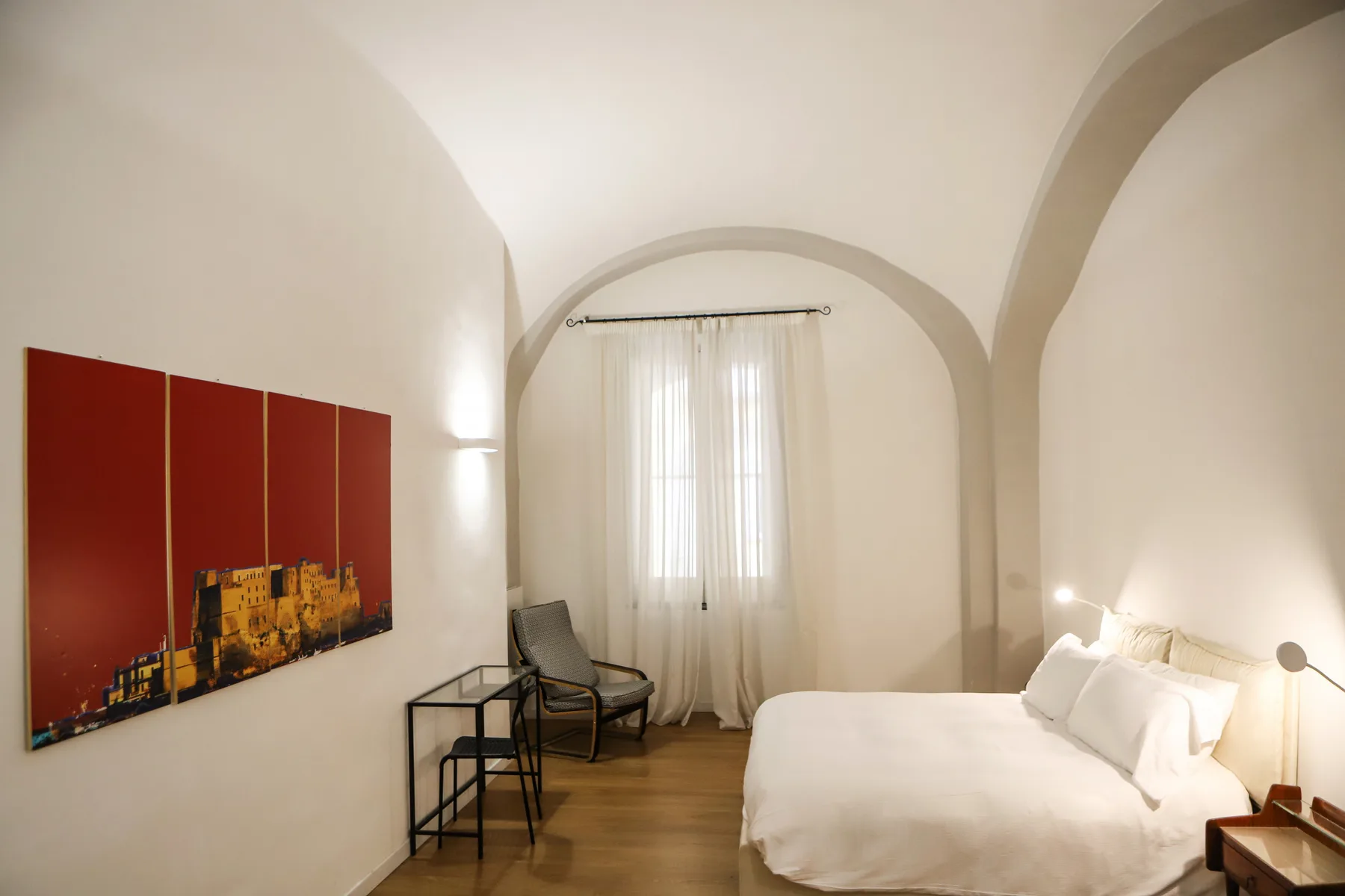 Un dormitorio con una cama, asientos y una ventana con cortinas.