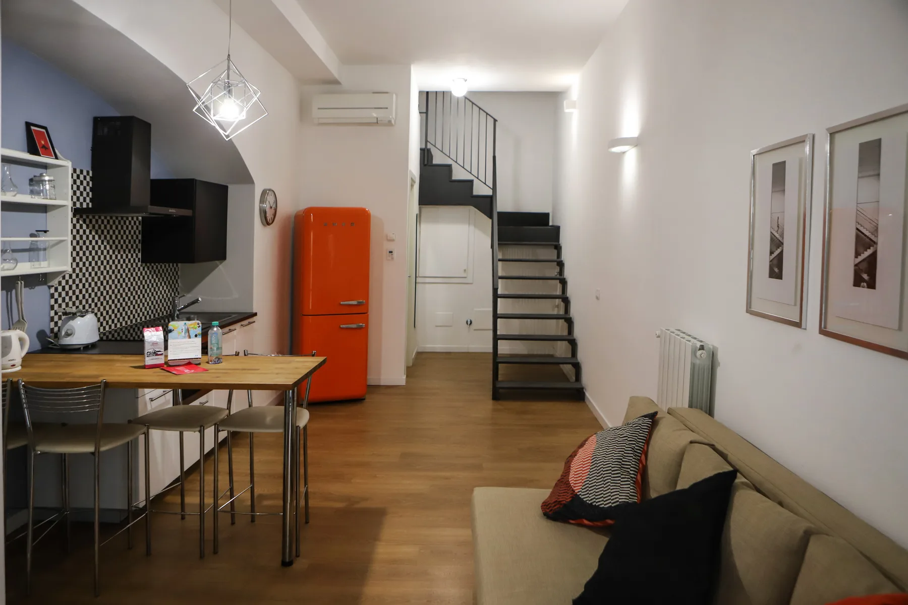 Una cocina compacta y un comedor se abren a una sala junto a una escalera.