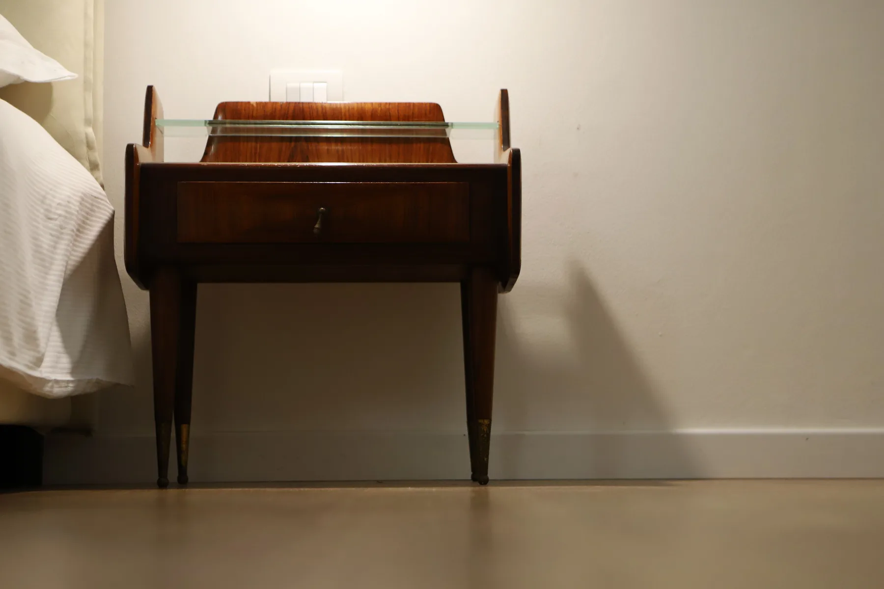 Escena de dormitorio con un escritorio oscuro de madera junto a una cama.
