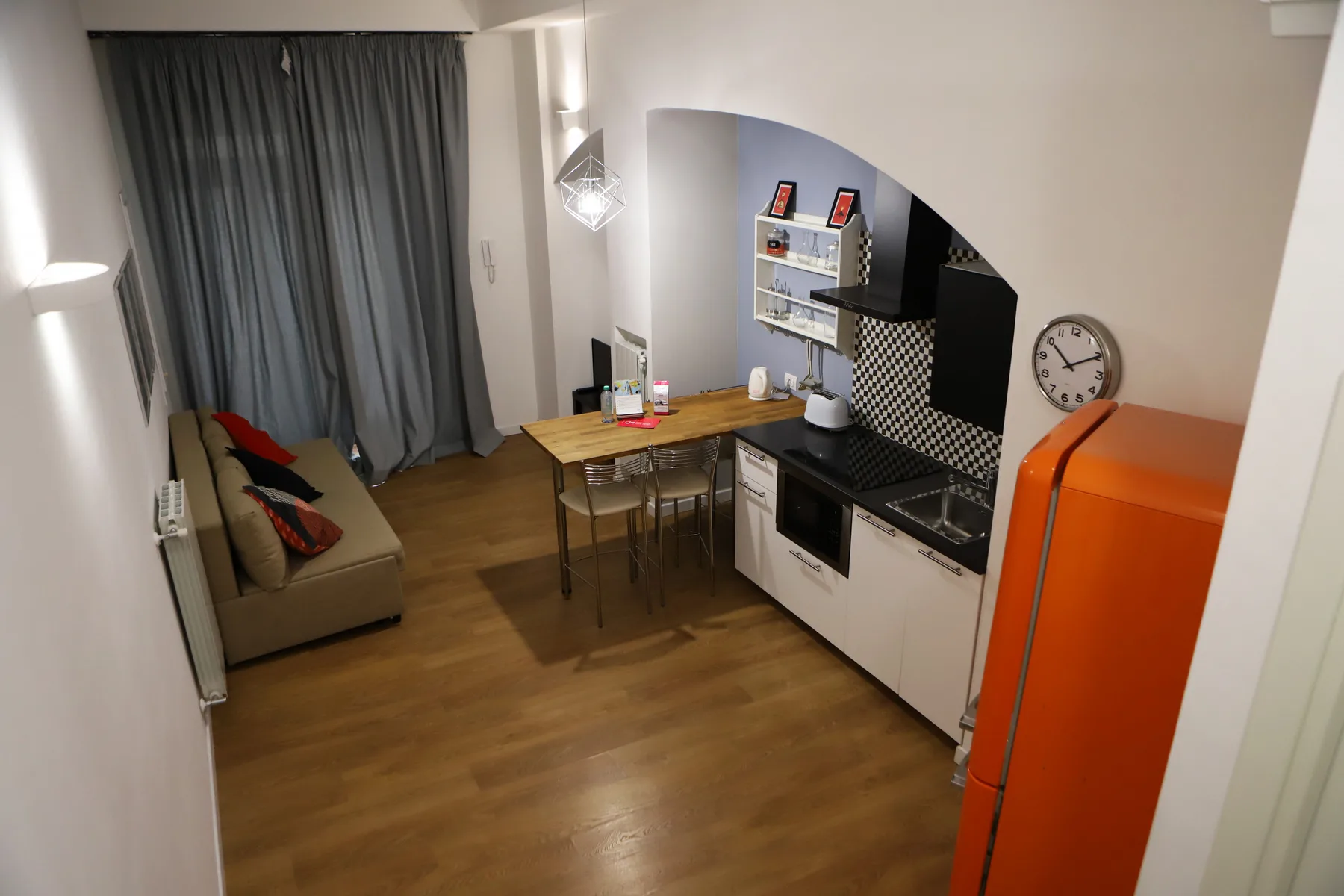 Una cocina compacta y zona de comedor con una mesa de madera junto a un sofá.